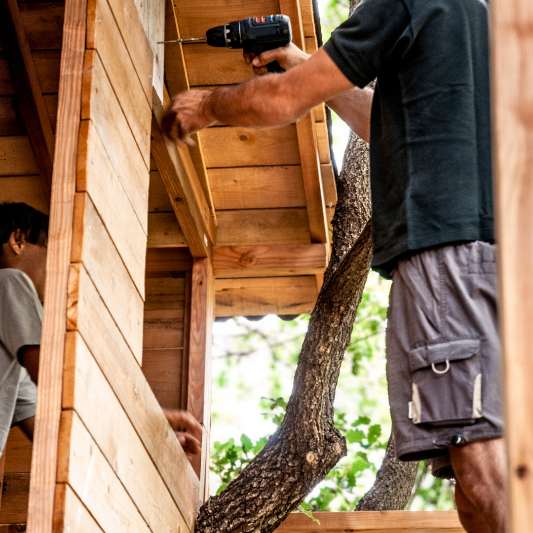 Dad and son putting on the finishing touches of a tree house.
